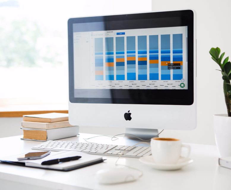 An iMac on a bright desk showing a sales dashboard