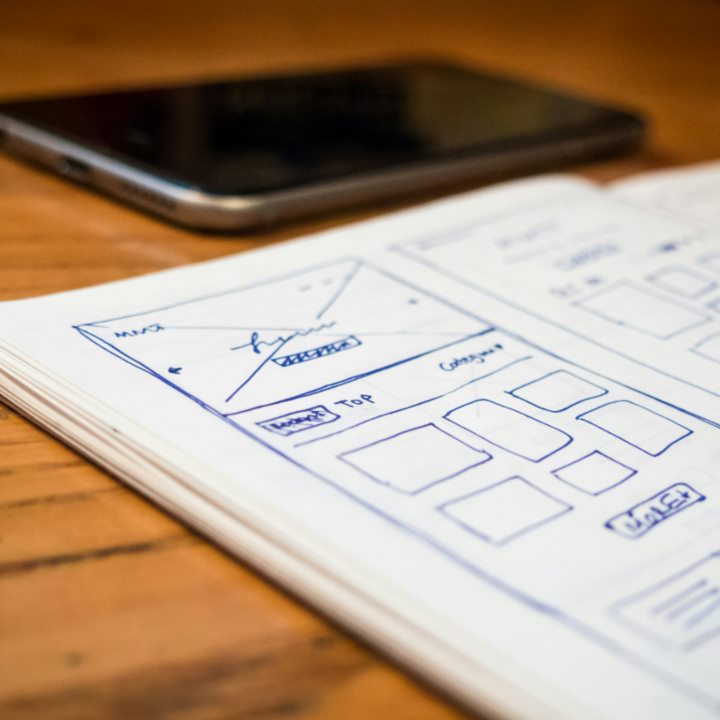 Website wireframe sketches in a notebook beside a phone