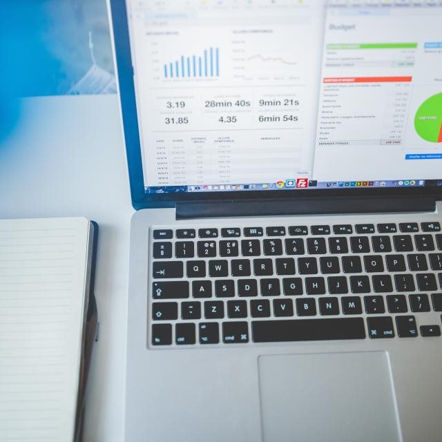 A laptop showing analytics charts beside a notebook