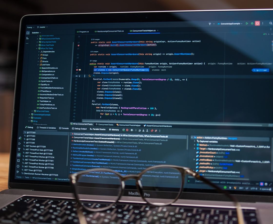 A laptop showing code beside a pair of glasses