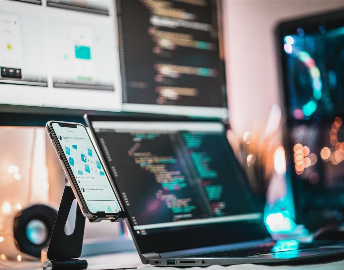 A phone showing an app beside a laptop with code